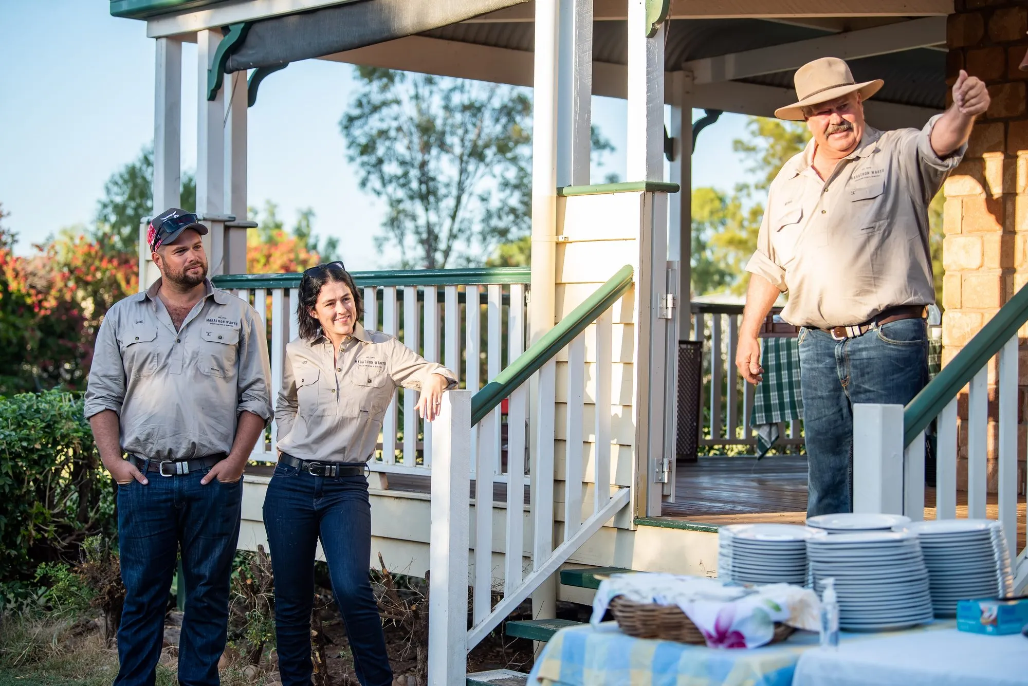 Three of the Marathon Wagyu team in station shirts beside the homestead verandah